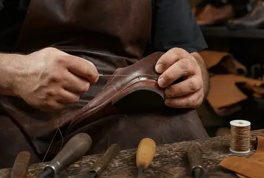 Profissional costurando um calçado com atenção aos detalhes.